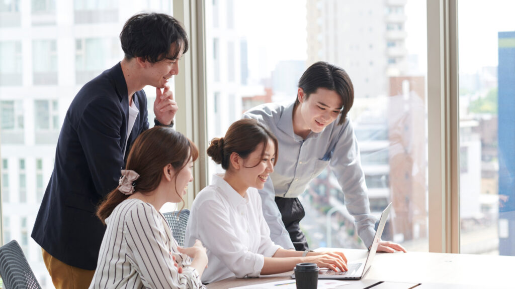 ノートパソコンを囲んで打ち合わせをする社員