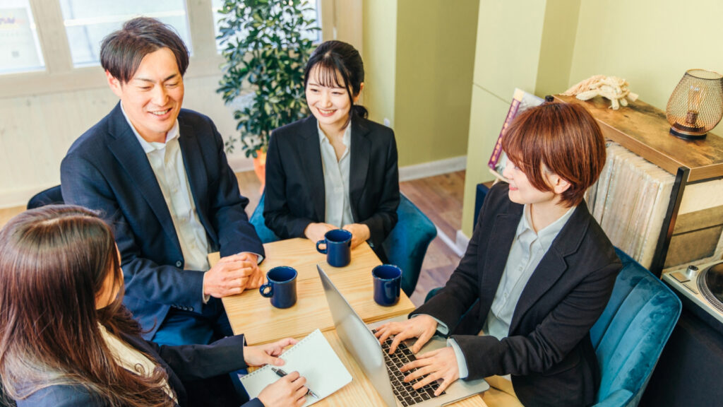 テーブルを囲んで談笑しながら打ち合わせをする社員